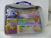 Full view of the sealed Platinum Membership Kit inside a clear zippered case showing the plush bear and various official club materials