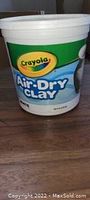 Closed bucket of Crayola Air-Dry Clay on wooden floor showing label and size.