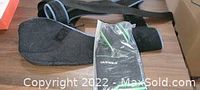 Photo showing used black arm sling with adjustable padded straps and three black and green ankle support sleeves, one still in original packaging.