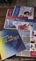 Lot showing two CPR and First Aid manuals and accompanying CDs from American Red Cross and American Heart Association, all used.