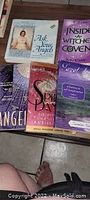 Wide view of six spiritual books, including titles about angels and witches, arranged on a surface