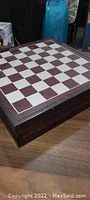 Closed wooden game box with a square board on top featuring alternating dark and light squares for chess or checkers.