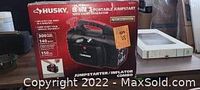 Boxed product showing Husky 8-in-1 Portable Jumpstart with Inflator Combo branding and features.