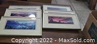 Six professionally framed panoramic nature photographs laid out on a table