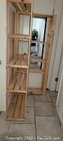 Photo showing two tall natural wood bookcases with multiple horizontal slatted shelves placed adjacent to each other in an indoor setting.