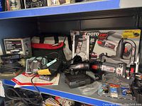 Bosch Roto Zip RZ20 drywall saw, standing on shelf with original box, carrying bag, bits, accessories, and soldering station and palm sander nearby.