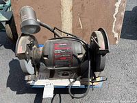 Front view of Craftsman bench grinder with visible wheels, motor body, work light, and power cord.