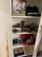 Shelf containing multiple sets of drill bits, cases, and Drill Doctor 500 box