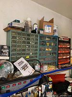 Overview of multiple metal and plastic organizers filled with assorted hardware on shelf with additional containers and items below.