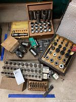 Bench shot showing wooden cases with collets, metal rack collets, drill chucks and adapters