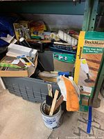 View showing assembled items including tote, rollers, brushes, tarp box, and paint trays in garage setting