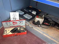 Photo of three power tools: Chicago Electric multi-function tool, Wen solderer in red case, Craftsman 7" sander on metal shelf.