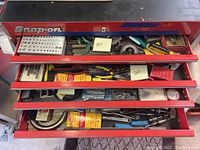 View of 4 drawers open in Snap-on red tool chest containing various hand tools, replacement parts, drill bits, and measuring devices
