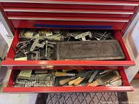 Top drawer with metal clamps and a metal mesh tray, along with several small metal parts and hardware packaged in plastic bags.