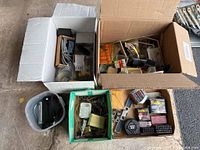 Overview of four boxes and containers filled with various tools, hardware, tape measures, and stamping sets.