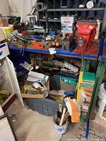 View of whole workbench showing wooden top, metal legs, lower shelf, and various hand tools scattered on top. Red bench vice attached but noted as not included.