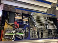 Drawer of assorted wrenches showing sets including ratcheting stubby wrench set, metric and SAE sizes in plastic organizer.