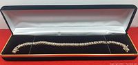 Complete bracelet in open black and white hinged display box on red background