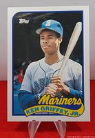 Front image of the 1989 Topps Traded Ken Griffey Jr. rookie baseball card with player posing in Mariners uniform and team name at bottom.