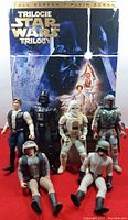 Six 1990's Star Wars action figures displayed in front of the Star Wars Trilogy full screen DVD case showing characters and scenes from the movies.