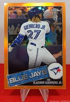 Front of 2020 Topps Chrome Orange Refractor Vladimir Guerrero Jr. baseball card showing player mid-swing in Blue Jays uniform with orange refractor border.