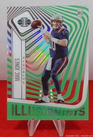 Front of 2021 Panini Illusions Football Mac Jones rookie card with green holographic illusion design and player image.