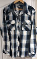 Long sleeve black, white, and blue plaid shirt hanging on hanger