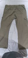 Green cargo pants laid flat showing back view with pockets