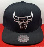 Front view of the black baseball cap showing the white embroidered Chicago Bulls logo on front panel and adjustable fit sticker on brim.