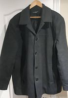 Full front view of dark grey pea coat hanging on hanger showing overall condition and button placement