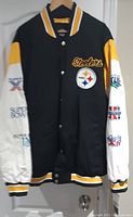 Front view of Pittsburgh Steelers winter jacket, showing black body, white sleeves with Super Bowl patches, yellow and white striped collar, cuffs, and hem.