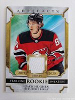 Front of 2019-2020 Upper Deck Artifacts Year One Rookie Sweaters card featuring Jack Hughes in New Jersey Devils jersey with embedded white jersey swatch.