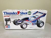 Front view of the boxed Thunder Shot Tamiya 1/14 scale RC car showing the car illustration and branding.