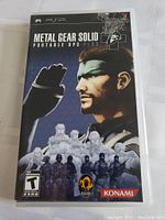 Front cover of the Metal Gear Solid Portable Ops Plus PSP game showing artwork featuring Snake and soldiers.