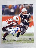 Full 8x10 signed photo showing Wes Welker running with football, evading Arizona Cardinals defender, signature visible in blue ink.