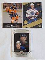 Three hockey cards featuring Connor McDavid in Oilers uniform, including Upper Deck and UD Artifacts series.