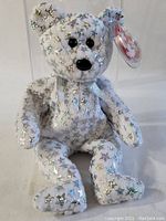 Close up of silver star-covered white Beanie Baby teddy bear with tag attached