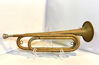 Side profile of the full brass bugle showing overall shape and condition.