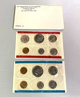 Two sealed plastic coin sets from 1972 US Mint in red and blue colored packaging with accompanying envelope and inserts from U.S. Treasury Department.