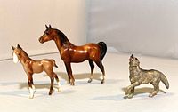 Front angle of bay large horse, foal, and wolf figurine showing condition and size relative to each other.