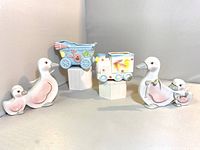 Photo showing the full set: baby carriage, toy train, and mother duck figurines with ducklings, placed on flat surface against a neutral background.