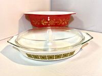 Photo showing red 2 1/2 quart casserole with golden floral poinsettia pattern and white interior, alongside the white divided casserole dish with avocado floral pattern, with clear glass lid in front.