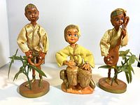 Front view of the three pixies showing their size, musical instruments, and bases with plant decorations