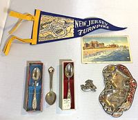 Full lot of vintage New Jersey souvenirs including pennant, postcard, spoons, pin, and tray displayed on flat surface