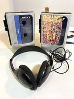 Front view of two vintage Sony Walkman cassette players with a black wired headset in front.