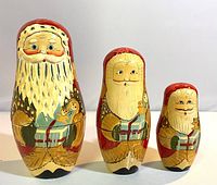 Three vintage wooden Santa nesting dolls in a row showing size variation and detailed hand-painted features