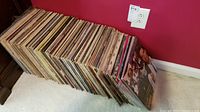 Rows of vinyl albums standing upright against a red wall