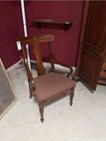 Full side view of the wood chair showing carved backrest, armrest shape, and upholstery seat.