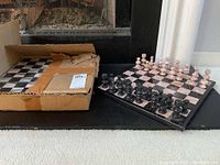 Chess set displayed on a black stone hearth with one set on board and the other in box