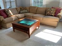 Full view of tan upholstered Ethan Allen sectional sofa with loose cushions and decorative pillows in a family room with natural light.